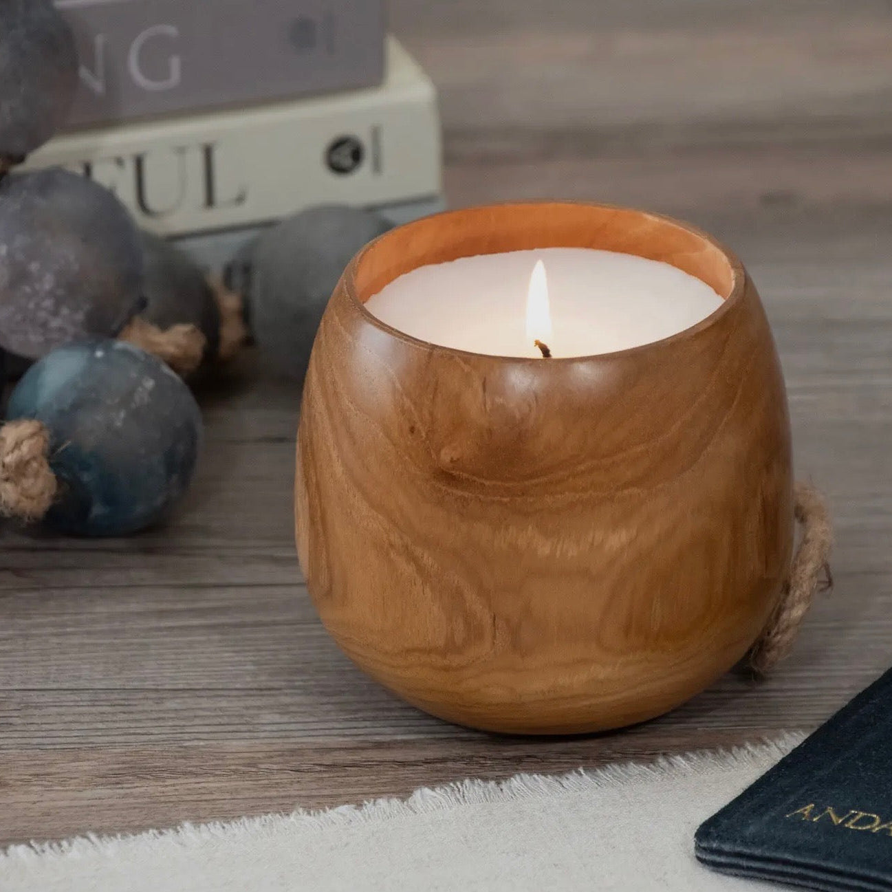 Wooden candle holder with a lit candle on a wooden surface