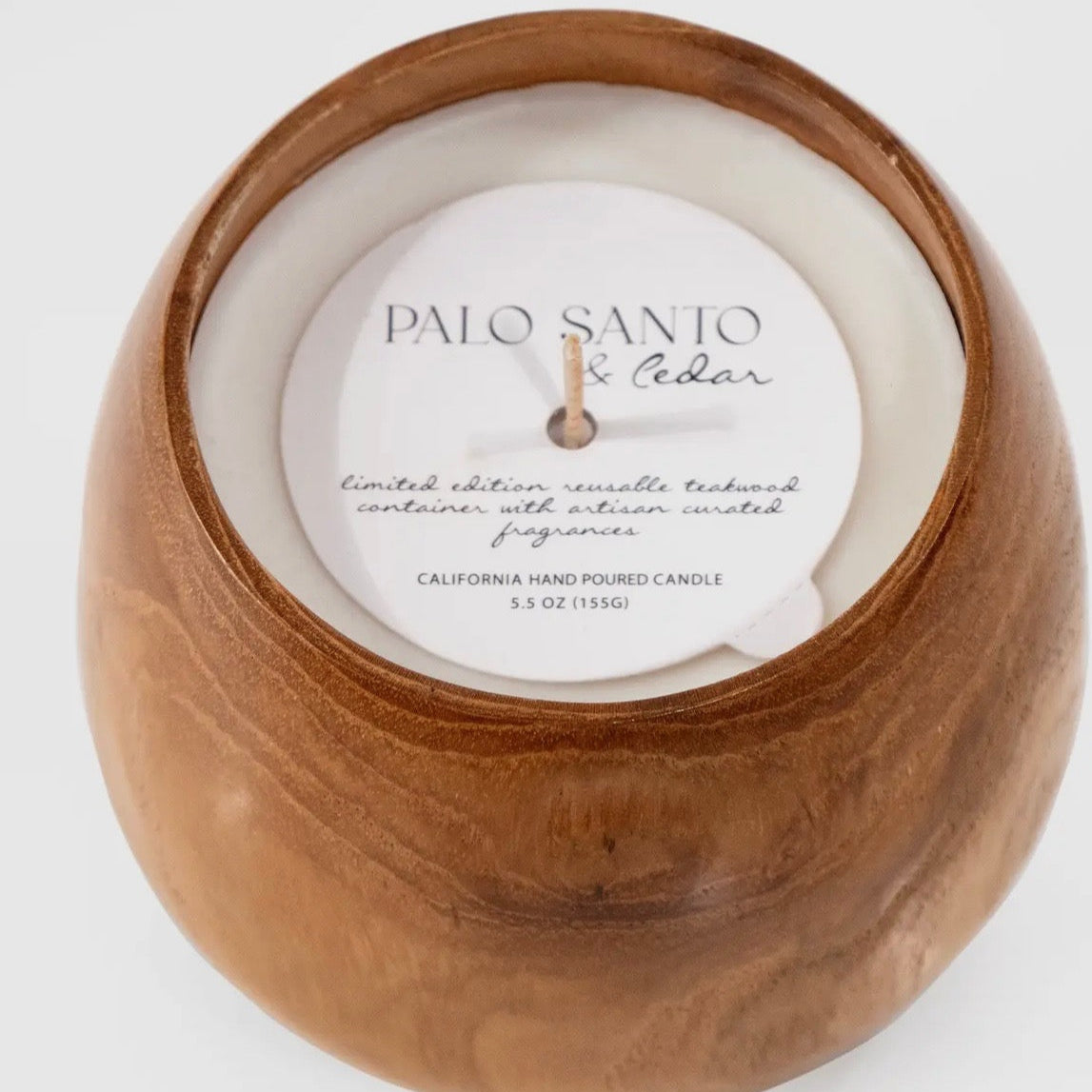 Candle in a wooden holder with 'Palo Santo & Cedar' label on a white background