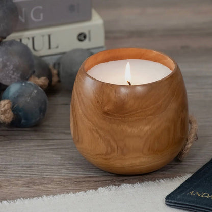 Wooden candle holder with a lit candle on a wooden surface