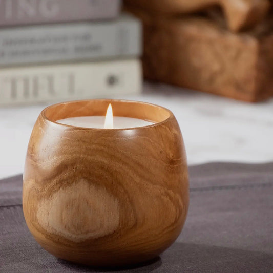 Wooden candle holder with a lit candle on a soft surface