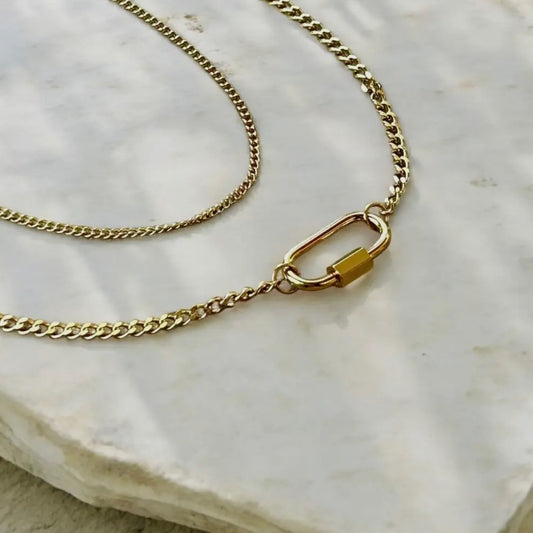 Gold chain necklace on a textured white surface
