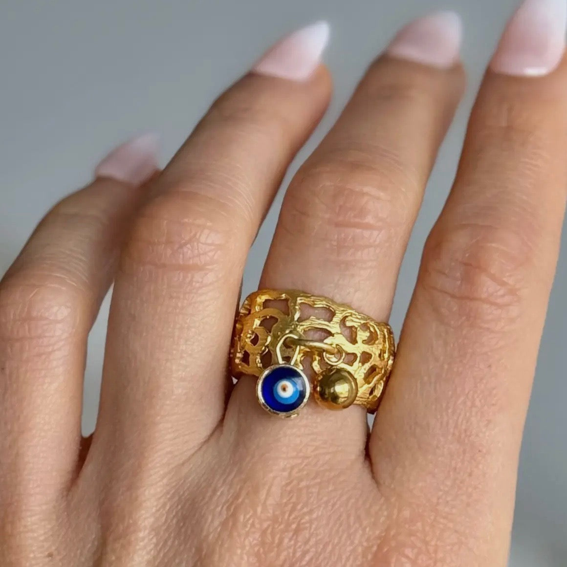 Gold ring with a blue stone on a hand against a neutral background