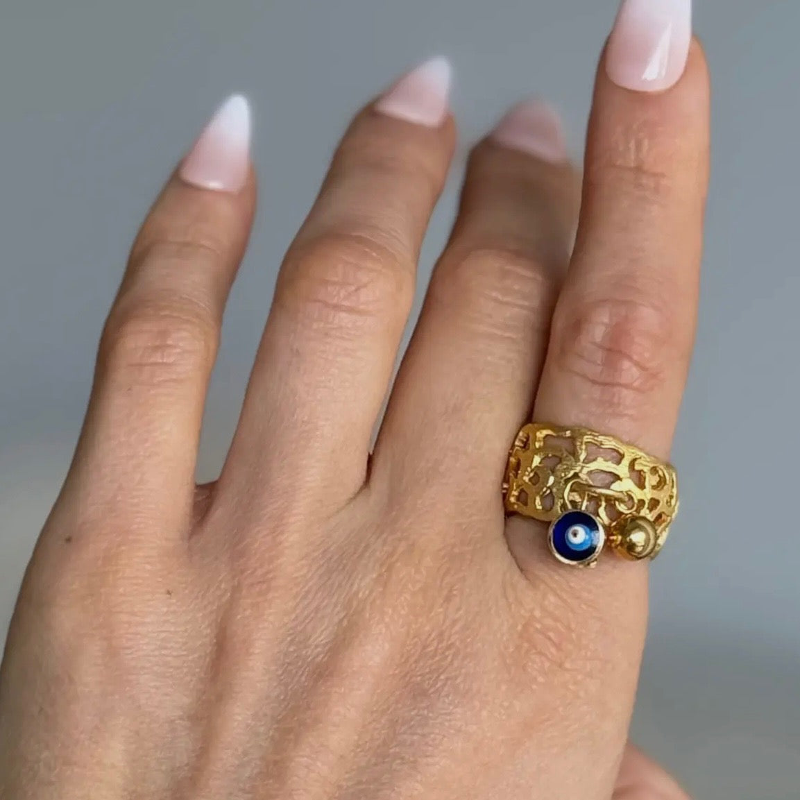Gold ring with a blue gemstone on a hand against a gray background